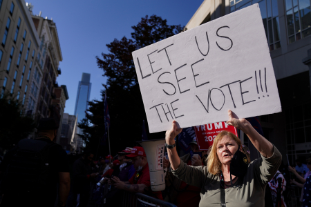 A Trump supporter holds up a sign advocating for increased transparency of the vote counting at the Pennsylvania Convention Center in Philadelphia, Pa. on Nov. 6, 2020.