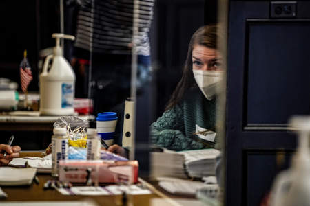 A masked poll worker is seen reflected in plexiglass inside a polling location at Houston Hall in Philadelphia, Pa. on Nov. 3, 2020.