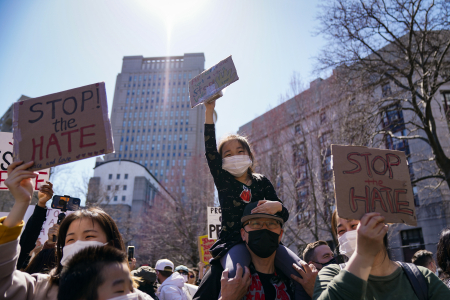 A girl sitting on her father's shoulders cheers during a Stop the Hate rally at Columbus Park in New York, N.Y. on March 21, 2021 