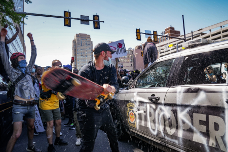 A protester breaks the window of a Pennsylvania State Police vehicle at Broad and Vine Streets in Philadelphia, Pa. on May 30, 2020.
