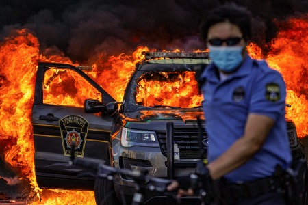 A Philadelphia Police officer walks away from a Pennsylvania State Police vehicle that was set on fire at Broad and Vine Streets in Philadelphia, Pa. on May 30, 2020.