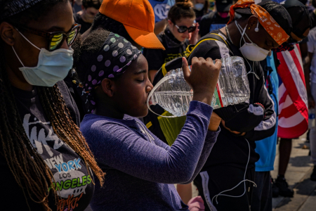 A young protester takes a drink from a gallon of water as people pray in front of the Philadelphia Museum of Art on June 4, 2020.