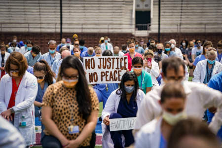 Doctors, nurses, and other healthcare workers kneel in silence during a protest at Franklin Field in Philadelphia, Pa. on June 5, 2020.