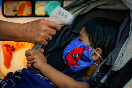 The younger brother of a camper has his temperature taken while entering the campus on June 29, 2020. Campers and their families underwent daily temperature checks upon entering the camp site.