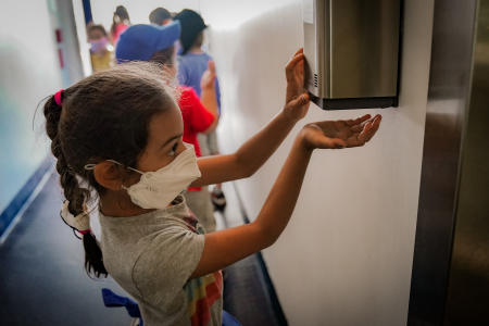 A camper in the six to seven-year-old division reaches for hand sanitizer under an automated dispenser outside the arts and crafts room on July 15, 2020. Campers and staff were required to use hand sanitizer or wash their hands in between every activity.