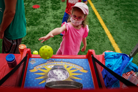 A camper attempts to throw a Wiffle ball into a bucket as a part of the camp carnival on Aug. 19, 2020. The carnival included mechanical rides, water slides, and a variety of classic carnival games.